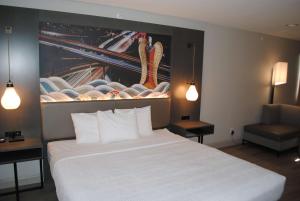 a hotel room with a large white bed and a chair at Best Western Plus Dragon Gate Inn in Los Angeles