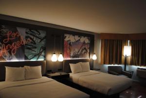 a hotel room with two beds and a chair at Best Western Plus Dragon Gate Inn in Los Angeles