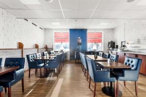 a dining room with wooden tables and blue chairs at Best Western Sjofartshotellet in Oskarshamn