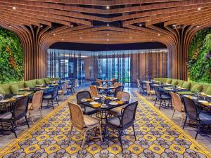 a restaurant with tables and chairs in a room at Grand Mercure Malang in Malang