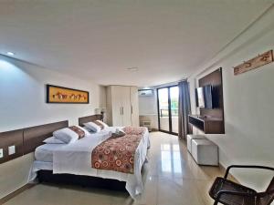 a hotel room with a bed and a television at GoldFlat in João Pessoa