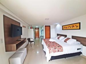 a bedroom with a large bed and a flat screen tv at GoldFlat in João Pessoa