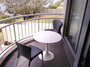 a balcony with a white table and two chairs at Kings Row Apartments in Caloundra