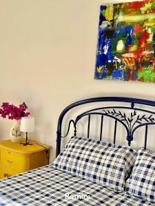 un letto con cuscino a scacchi e un dipinto sul muro di Il mare di Ciccio ad Avola