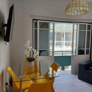 uma sala de estar com uma mesa de vidro e cadeiras amarelas em RIVERINN Casa Familiar T 3 c Acesso Terraço 1 andar em Portimão