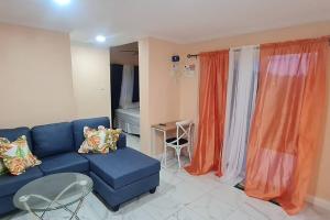 ein Wohnzimmer mit einem blauen Sofa und orangefarbenen Vorhängen in der Unterkunft The Den & Deck in Anse La Raye