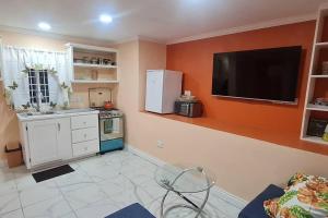 a kitchen with a refrigerator and a tv on the wall at The Den & Deck in Anse La Raye