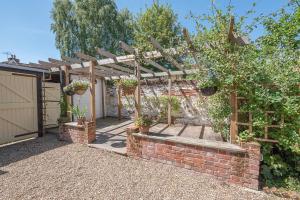 a garden with a brick wall and a wooden pergola at Abigail's Cottage Air Manage Suffolk in Woodbridge