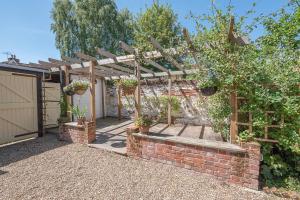 a garden with a brick wall and a wooden pergola at Abigail's Cottage, Wickham Market in Woodbridge