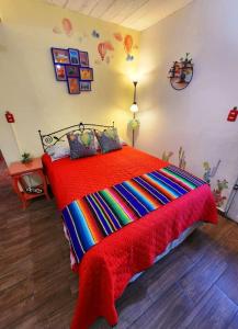 a bedroom with a colorful bed with a red blanket at LA CASITA YALI in San Martín de las Pirámides