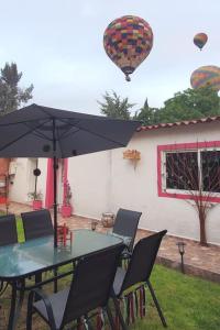 einen Tisch und Stühle mit einem Regenschirm und einem Heißluftballon in der Unterkunft LA CASITA YALI in San Martín de las Pirámides