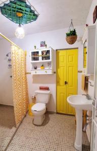 La salle de bains est pourvue d'une porte jaune, de toilettes et d'un lavabo. dans l'établissement LA CASITA YALI, à San Martín de las Pirámides