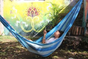 a young girl laying in a hammock with a cell phone at Garra Charrua in Mérida