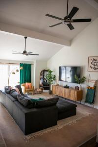 a living room with a black couch and a flat screen tv at Fun 4 BR Rexburg Retreat and Game Room, Sleeps 12 in Rexburg