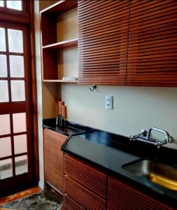 La cuisine est équipée d'un évier et de placards en bois. dans l'établissement Apartamento Rua Torta, à Gramado