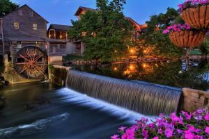 a pond with a waterwheel and a mill at night at Colonial Crest 107 - Great location! - You can walk to town! condo in Pigeon Forge
