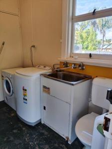 a small bathroom with a sink and a washing machine at Seaside Cottage with Jetty in Point Clare