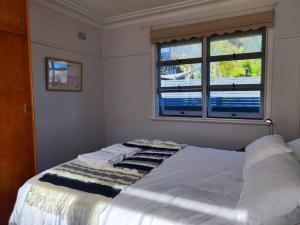a bedroom with a white bed with a window at Seaside Cottage with Jetty in Point Clare