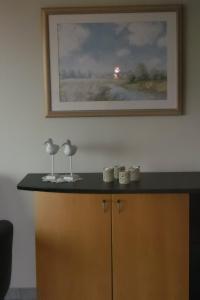 a painting on a wall with two glasses on top of a cabinet at Residence Scorpio in Nieuwpoort