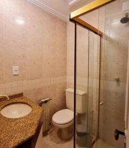 y baño con aseo, lavabo y ducha. en Apartamento Rua Torta, en Gramado