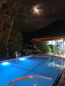 uma grande piscina azul à noite com um carro em Casa com Piscina Canto do Forte - Praia Grande na Praia Grande