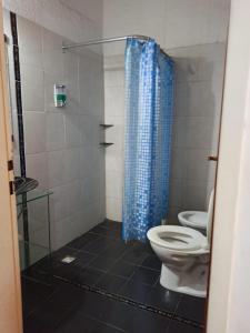 baño con aseo y cortina de ducha azul en Habitaciones el Beto en San Luis