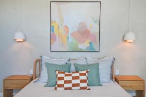 łóżko z niebiesko-białymi poduszkami i obrazem w obiekcie Element on Coolum Beach w mieście Coolum Beach