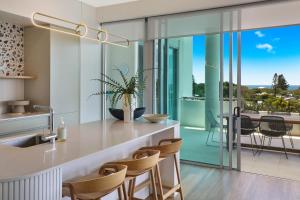 a kitchen with glass walls and a counter with chairs at Element on Coolum Beach in Coolum Beach