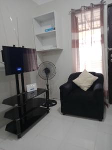 a living room with a black couch and a television at Cozy9-14 2BR at Mandaue City in Mandaue City