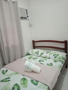 a bed with a green bedspread with a roll on it at Cozy Staycation at Mandaue City in Mandaue City