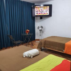 a room with two beds and a flat screen tv at Lima Airport Hostel with FREE AIRPORT PICK UP in Lima