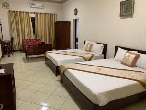 a hotel room with two beds and a chair at Gold Rooster Resort in Phan Rang–Tháp Chàm
