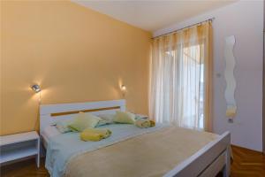 a bedroom with a bed with yellow walls and a window at Apartments with a parking space Losinj, Losinj - 20184 in Mali Lošinj