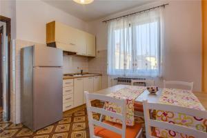 a kitchen with a table and chairs and a refrigerator at Apartments with a parking space Losinj, Losinj - 20184 in Mali Lošinj