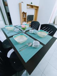 une table avec des bols, des assiettes et des ustensiles dans l'établissement Cozy 3 Bedroom Apartment Bandar Perda BM, à Bukit Mertajam