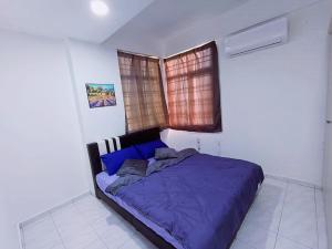 ein Schlafzimmer mit einem Bett mit blauer Bettdecke und einem Fenster in der Unterkunft Cozy 3 Bedroom Apartment Bandar Perda BM in Bukit Mertajam