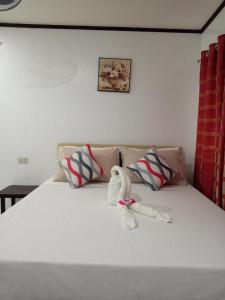 a bed with two stuffed animals sitting on it at Jupiters Garden Cottages in Lawa-an