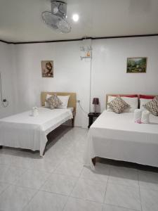 Jupiters Garden Cottages في Lawa-an: سريرين في غرفة بجدران بيضاء