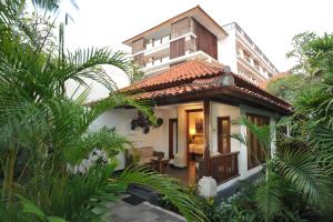 uma casa de hóspedes com uma varanda e um edifício em Puri Raja Hotel em Legian
