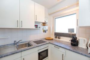 a kitchen with white cabinets and a sink and a window at Strandhochhaus 88 in Döse