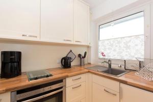 a kitchen with white cabinets and a sink and a window at Strandhochhaus 5 in Döse