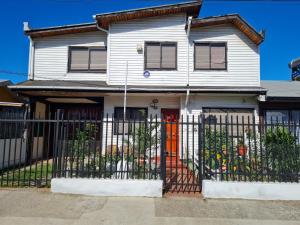 une maison blanche avec une porte rouge et une clôture dans l'établissement Hospedaje JUALIC, à Valdivia