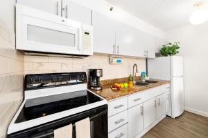 eine Küche mit weißen Schränken und einem Herd mit Backofen in der Unterkunft Charming Condo Steps from Waikiki Beach with Parking! in Honolulu + 53 Fotos