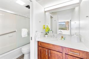 ein Badezimmer mit Waschbecken, Toilette und Spiegel in der Unterkunft Charming Condo Steps from Waikiki Beach with Parking! in Honolulu