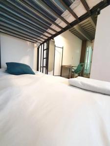 Una cama blanca grande con una almohada azul. en Habitación privada c/ terraza &escritorio Polanco., en Ciudad de México
