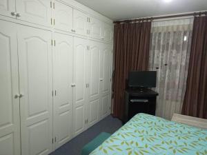 拉巴斯的住宿－acogedor departamento，卧室配有白色橱柜、床和电视。