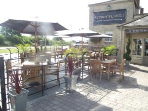 ein Café im Freien mit Tischen, Stühlen und Sonnenschirmen in der Unterkunft Sturdys Castle in Kidlington
