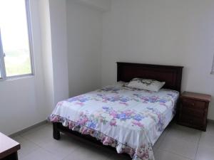 Apartment in Sirenis Atacames في تونسوبا: غرفة نوم مع سرير مع لحاف من الزهور