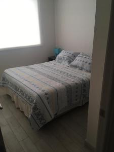 a bed in a white bedroom with a window at DEPARTAMENTO EN LA SERENA A PASOS DE LA PLAYA in La Serena