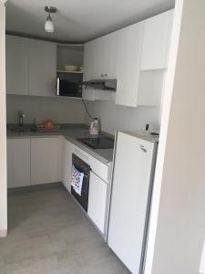 a kitchen with white cabinets and a white refrigerator at DEPARTAMENTO EN LA SERENA A PASOS DE LA PLAYA in La Serena